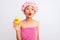 Chinese woman wearing shower towel and cap holding duck toy over isolated white background scared in shock with a surprise face,