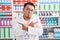 Chinese young man working at pharmacy drugstore pointing to both sides with fingers, different direction disagree