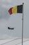 A chinook helicopter flying behind a belgian flag on a flag pole