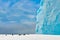 Chinstrap Penguins - Pygoscelis antarctica - on snow covered hill with huge turquoise iceberg in background, Antarctic Peninsula.