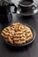 Chip cookies with peanuts and chocolate strips on plate on black table