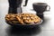 Chip cookies with peanuts and chocolate strips on plate on black table