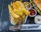 Chips in a metal basket, a background crusty white bread with se