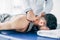 Chiropractor massaging neck of man lying on Massage Table