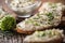 Chive cream cheese spread on a bread slice next to bunch of freshly cut chives and a bowl of spread in the background