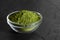 Chlorella green powder in a bowl on a black background. Seaweed natural supplement. Spirulina powder. Closeup