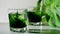 Chlorophyll extract is poured in pure water in glass against a white grey background with green leaf