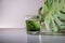 Chlorophyll extract is poured in pure water in glass against a white grey background with green leaf