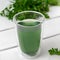 Chlorophyll water in a glass cup with green leaves on white wooden table