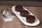 Chocolate alfajor on a white platter, with fresh blueberries, sugar and several. on a wooden table and dark background