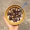 Chocolate Banana Raw Vegan Smoothie Bowl. Hand Holding Plate with Healthy Organic Breakfast.