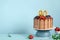Chocolate birthday cake with berries, cookies and number ninety golden candles on blue wall background, copy space