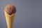 Chocolate brown creamy ice cream in crisp waffle cone on pastel grey background, closeup, details, top, half.