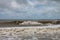 Chocolate brown waves roll toward the shore under a stormy sky after a hurricane