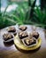 Chocolate brownie cubes with chocolate drizzle in paper cups on a wooden background