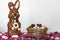 Chocolate bunny and bird nest full of easter almond eggs on white background