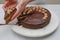 Chocolate cake with chocolate cream and chocolate ganache close up. Woman hands serving cake