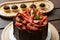 Chocolate cake covered with strawberries, basil leaves, blackberry jam and with chocolate plates around it_Brigadier in the backgr