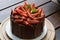 Chocolate cake covered with strawberries, basil leaves, blackberry jam and with chocolate plates around it. on the wooden table.