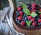 Chocolate cake with mascarpone on rustic background with raspberries, blueberries and mint leaves.