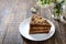 Chocolate cake with nut cream on a wooden table. A piece of cake on a plate