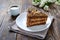 Chocolate cake with nut cream on a wooden table. A piece of cake on a plate and a cup of coffee