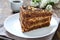 Chocolate cake with nut cream on a wooden table. A piece of cake on a plate and a cup of coffee