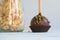 Chocolate cake pops with coconut flakes on a light background. Mini cakes on a wooden stick. A popular sweet dessert