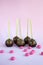 Chocolate cake pops with coconut flakes on a pink background. Mini cakes on a wooden stick. A popular sweet dessert
