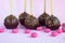 Chocolate cake pops with coconut flakes on a pink background. Mini cakes on a wooden stick. A popular sweet dessert