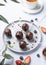 Chocolate cake pops with nuts on a plate with fresh berries and cup of tea on a light background. Homemade healthy candies on a