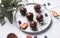 Chocolate cake pops with nuts on a plate with fresh berries on a light background. Homemade healthy candies on a stick