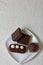 Chocolate cake pops and pieces of black chocolate on a white plate. Next to the potato cake. On the surface covered with white