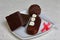 Chocolate cake pops and pieces of black chocolate on a white plate. Next to the potato cake. On the surface covered with white