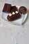 Chocolate cake pops and pieces of black chocolate on a white plate. Next to the potato cake. On the surface covered with white