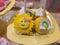 Chocolate cake, small, covered in yellow chocolate decorated with a smiling sun face and with rainbow served on a stick.