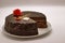 Chocolate cake on a white background. Image from above. The cake is decorated with a red flower of cream