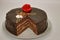 Chocolate cake on a white background. Image from above. The cake is decorated with a red flower of cream