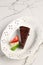 Chocolate Cake on a White Marble Table. A Piece of Brownie on a White Plate with Strawberry and Cream