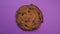 Chocolate chip cookie close-up, macro shot, fast spinning on a rotating purple background.