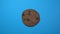 Chocolate chip cookie close-up, macro shot, slowly spinning on a rotating blue background.