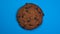 Chocolate chip cookie close-up, macro shot, slowly spinning on a rotating blue background.