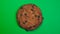 Chocolate chip cookie close-up, macro shot, slowly spinning on a rotating green background.