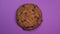 Chocolate chip cookie close-up, macro shot, slowly spinning on a rotating purple background.