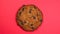 Chocolate chip cookie close-up, macro shot, slowly spinning on a rotating red background.