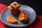 Chocolate chip cookies and piece of orange on plate and on red and black background with place for text selective focus with copys