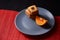 Chocolate chip cookies and piece of orange on plate and on red and black background with place for text selective focus with copys