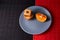 Chocolate chip cookies and piece of orange on plate and on red and black background with place for text selective focus with copys