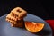 Chocolate chip cookies and piece of orange on plate and on red and black background with place for text selective focus with copys