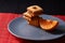 Chocolate chip cookies and piece of orange on plate and on red and black background with place for text selective focus with copys